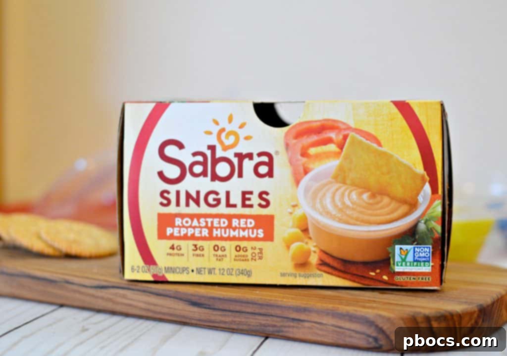 Close-up of a child's hand reaching for a cracker in a colorful DIY lunchable box.