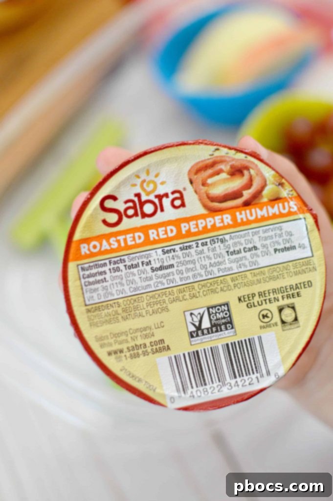 Sabra Hummus Singles displayed alongside crackers, bell peppers, and carrots.