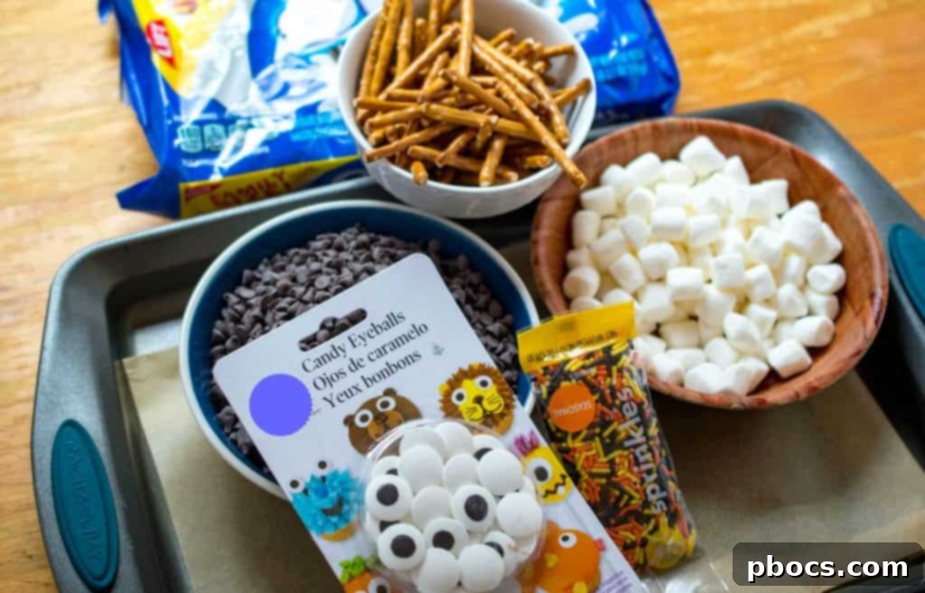 Assortment of Halloween Candy Bark Ingredients: Chocolate Chips, Candy Eyes, Oreos, Pretzels, Sprinkles, and Marshmallows