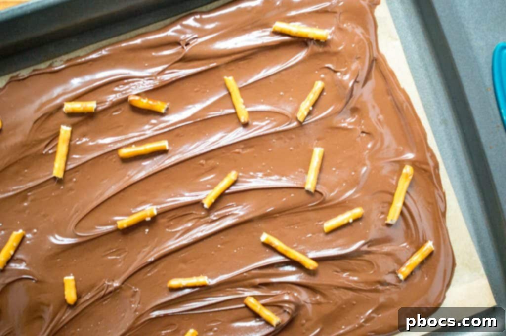 Spreading melted chocolate evenly on parchment paper for Halloween bark