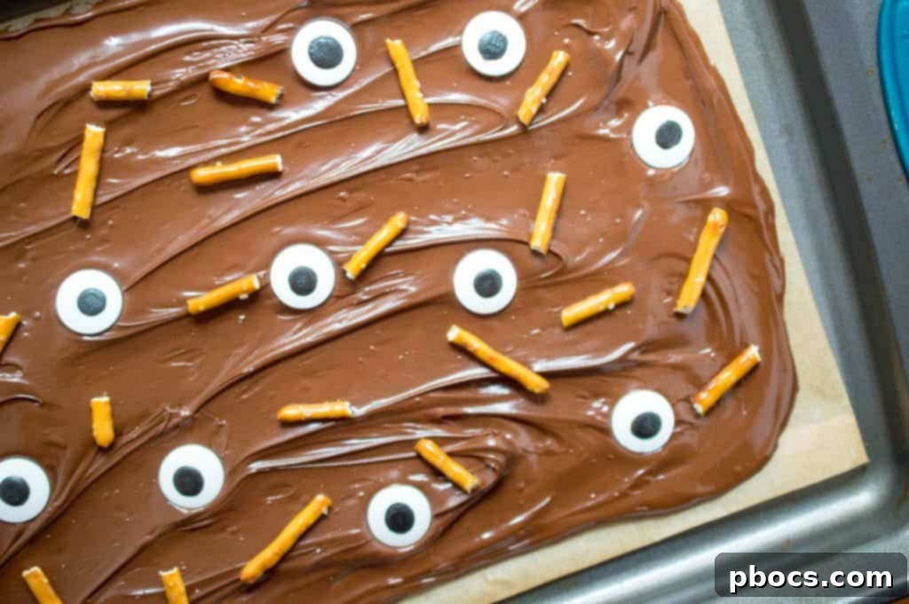 Adding broken pretzels to melted chocolate for Halloween candy bark