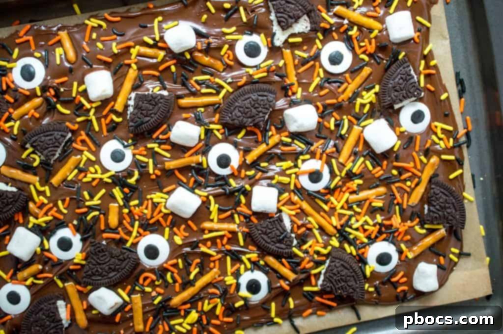 Close-up of Halloween bark being topped with broken Oreo cookies and festive sprinkles