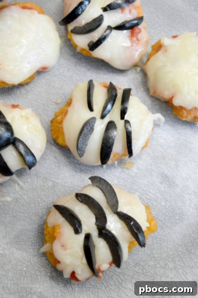 Melted cheese and tomato sauce on chicken nuggets, forming the base for spider bites.