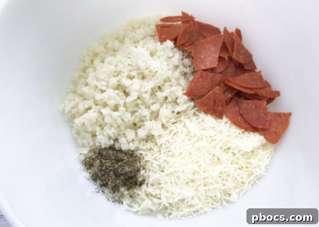 Preparing the riced cauliflower and seasoning for the Keto Pizza Casserole, showing ingredients in a bowl