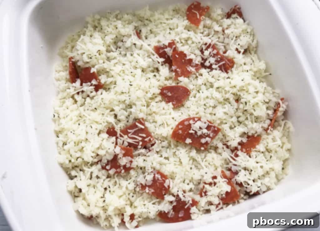 Adding quartered pepperoni slices to the cauliflower mixture for full flavor distribution in the Keto Pizza Casserole