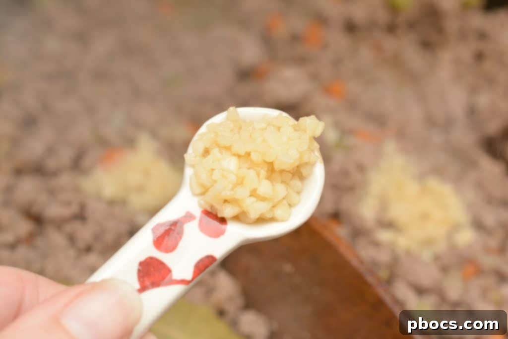 Adding minced garlic to the bolognese sauce