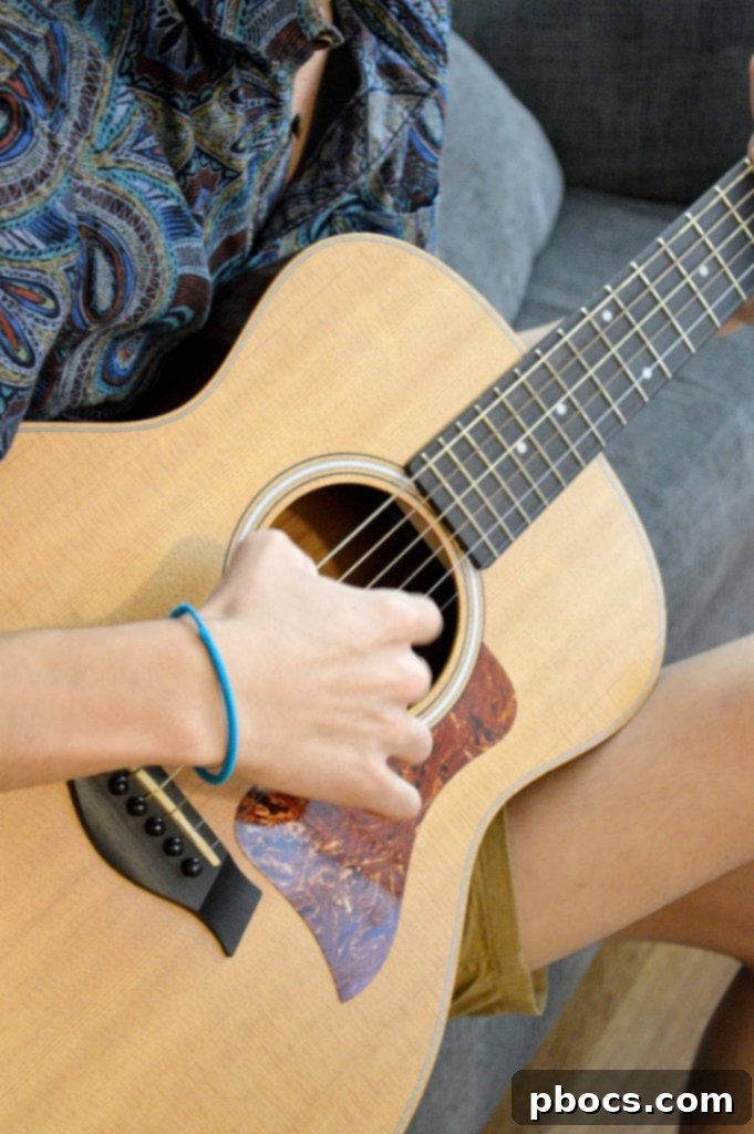 A young person enthusiastically playing an acoustic guitar, surrounded by musical instruments.