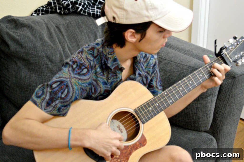 A close-up shot of a young person's hands skillfully playing chords on an acoustic guitar.