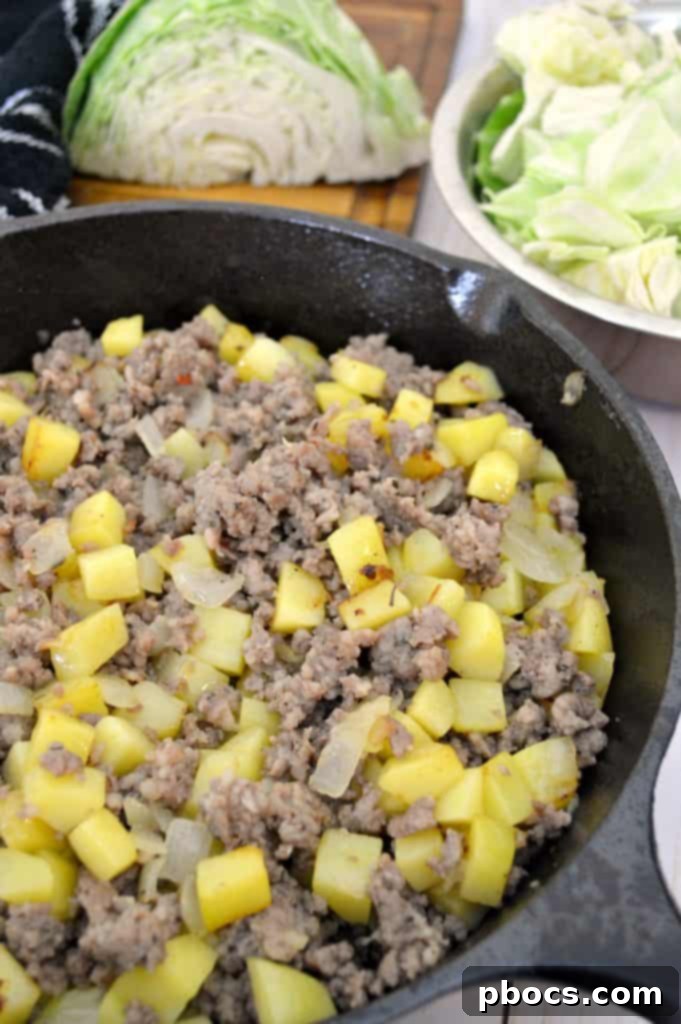 Sausage cooking in a skillet with potatoes and onions