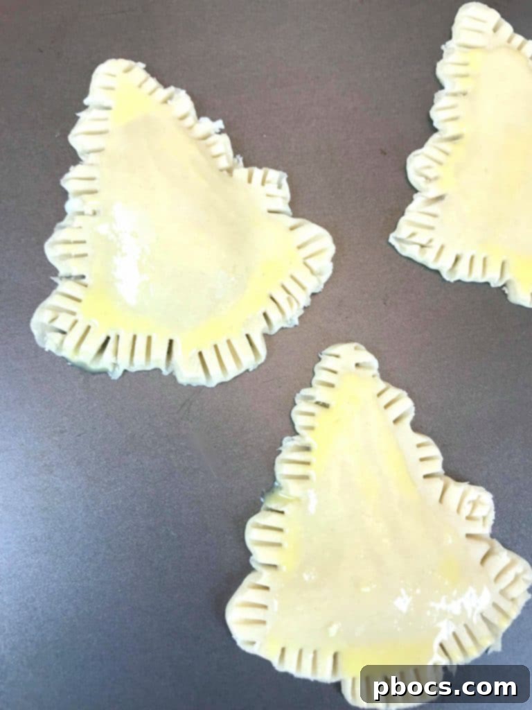 No-Fuss Festive Tree Treats 11 Brushing raw Christmas tree pastries with egg wash before baking.