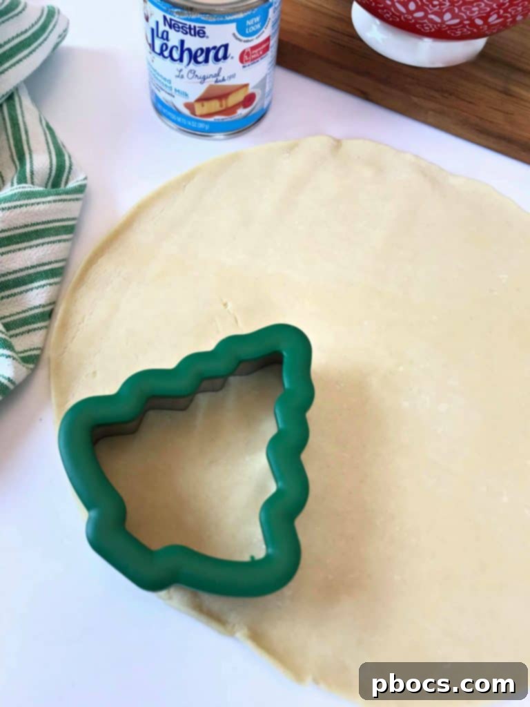 No-Fuss Festive Tree Treats 8 Cutting out Christmas tree shapes from pie crust with a cookie cutter.
