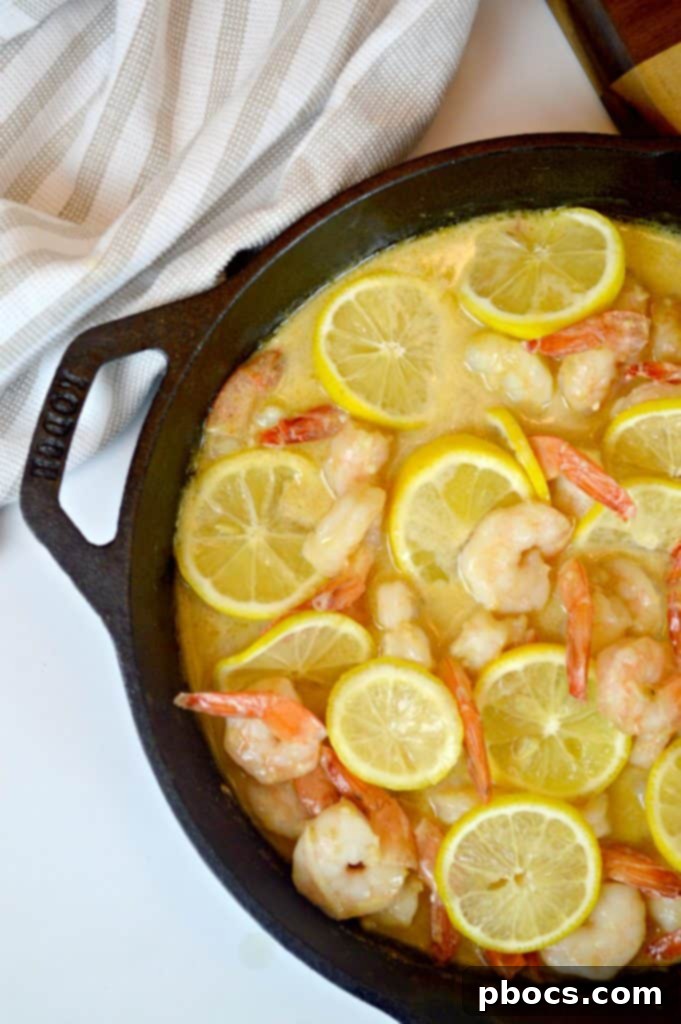 Creamy lemon parmesan sauce thickening in a skillet, ready for the cooked shrimp.