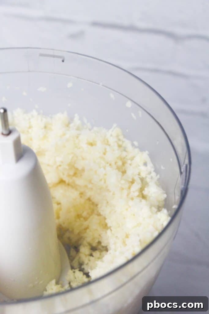 Creamy Keto Cauliflower Mash 7 Cooked cauliflower being pureed in a food processor for creamy mashed potatoes.