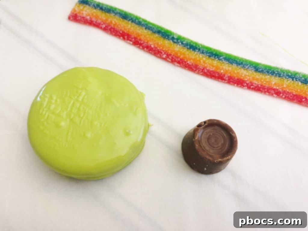 An OREO cookie being dipped into melted green candy melts, showing full coverage.