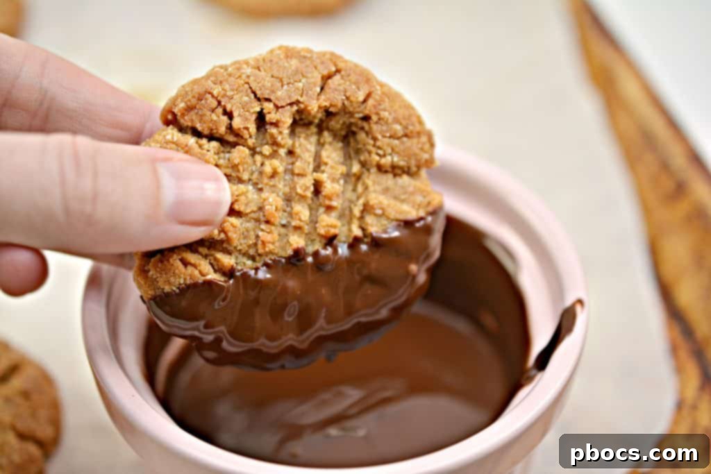 Dipping a keto peanut butter cookie into melted chocolate