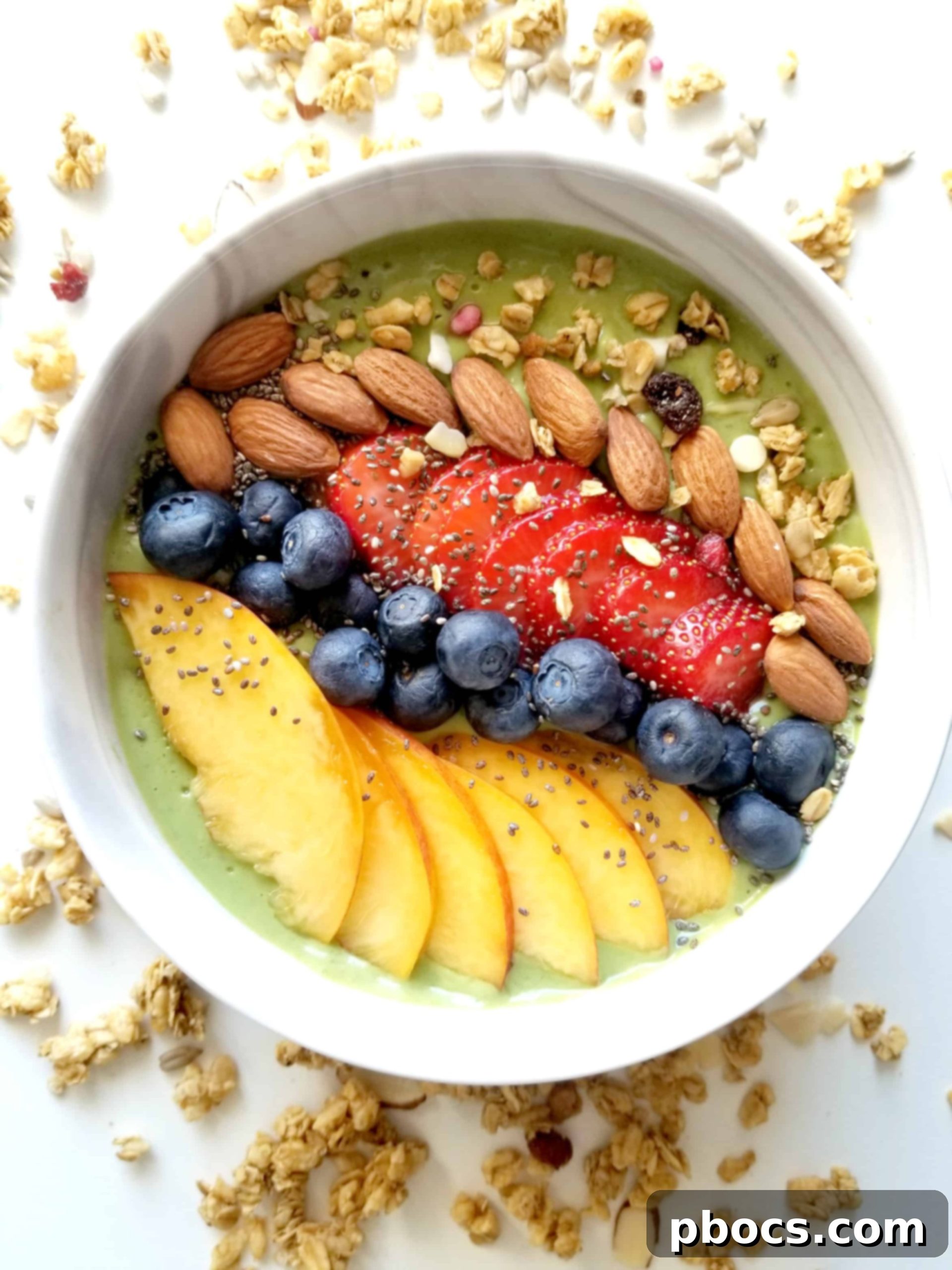 Beautifully presented green smoothie bowl topped with fresh peaches, blueberries, and strawberries