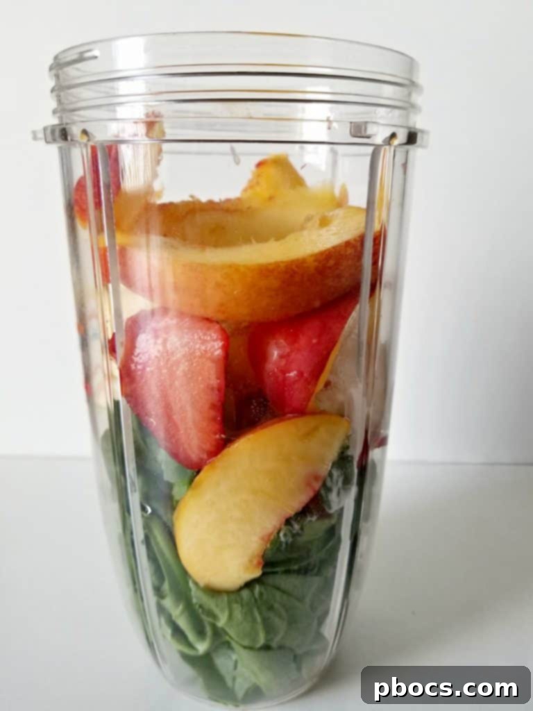 Fresh ingredients for a green smoothie bowl: spinach, Greek yogurt, strawberries, banana, peach, and orange juice ready to be blended