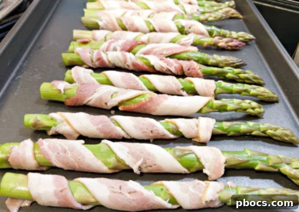 Hand wrapping bacon around asparagus