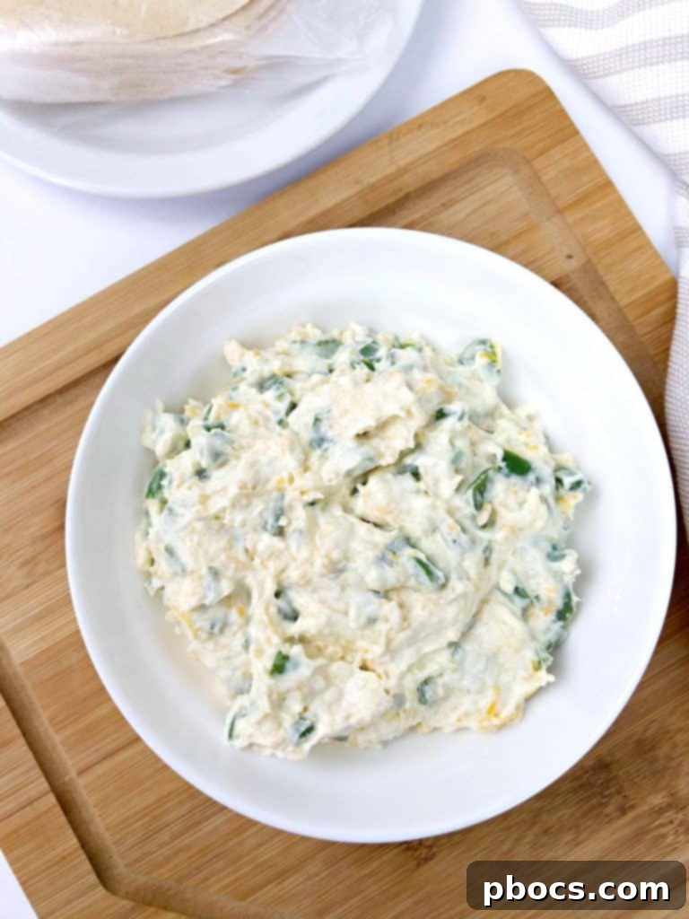 Mixing cream cheese, cheddar, and charred jalapenos for empanada filling