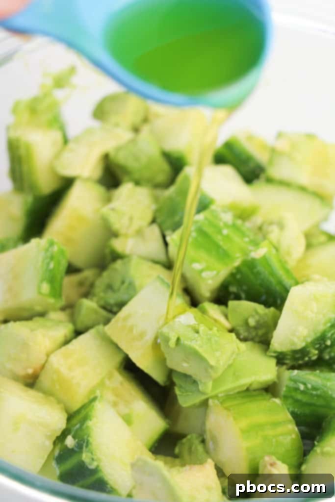 Avocado and cucumber salad being tossed for perfect coating