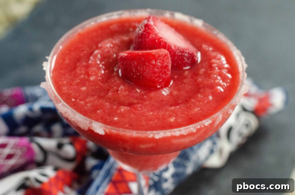 Close-up of a refreshing Frozen Strawberry Rhubarb Margarita with condensation on the glass, ready to be enjoyed