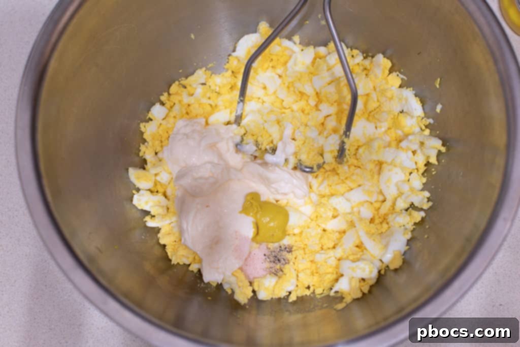 Adding homemade mayonnaise and seasonings to mashed eggs