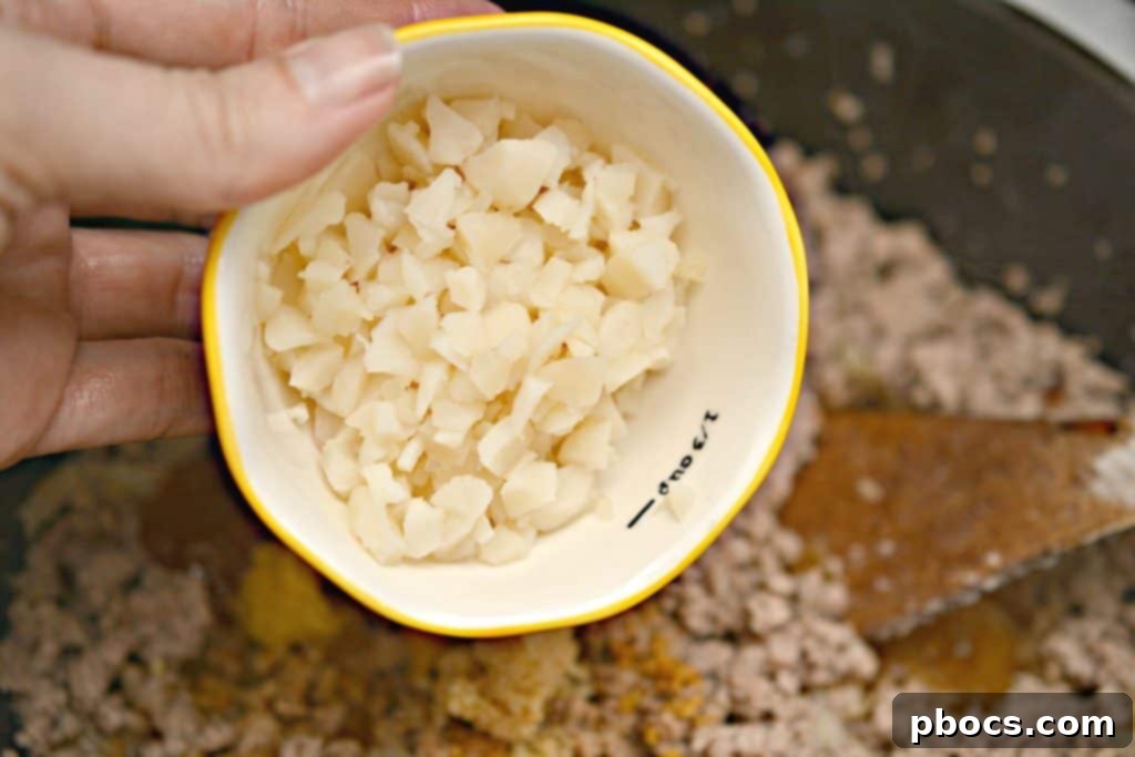 Adding Water Chestnuts Stirring in water chestnuts to the meat filling