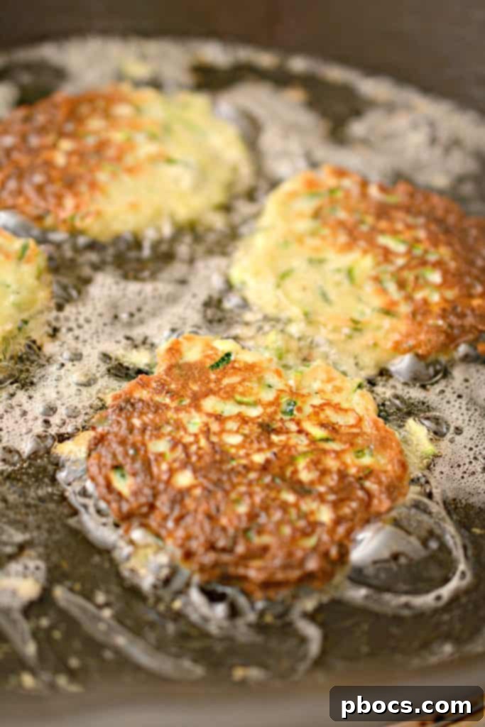 Savory Keto Zucchini Bites 13 Keto Zucchini Fritters cooking in a skillet until golden brown.