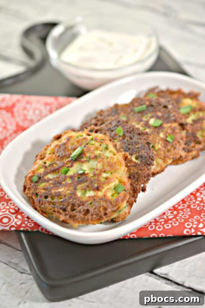 Savory Keto Zucchini Bites 14 Cooked Keto Zucchini Fritters draining on a paper towel-lined plate.