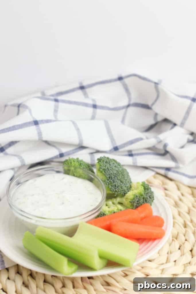 A large serving bowl of Greek Yogurt Veggie Dip on a rustic wooden board, ready for a gathering