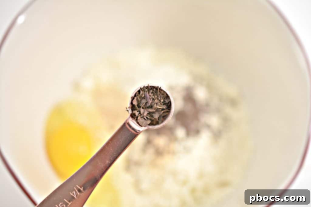 A bowl containing shredded mozzarella, grated parmesan, an egg, and spices, ready to be mixed for keto cheese buns.
