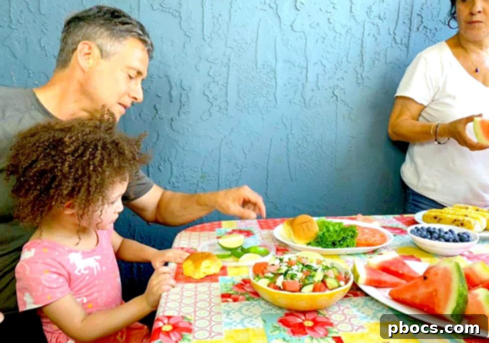 First Cookout with Watermelon Jalapeno Feta Salad 5 A beautifully set outdoor table for a summer gathering, featuring an array of dishes including burgers, salads, and grilled corn under ambient lighting.