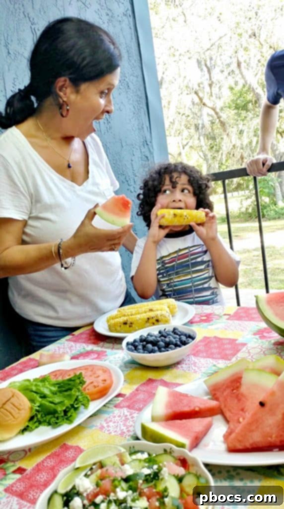 First Cookout with Watermelon Jalapeno Feta Salad 9 A child happily enjoying a grilled ear of corn, with butter dripping, at a lively summer gathering, highlighting the simple joy of fresh food.