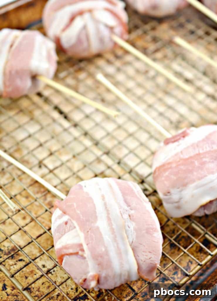 Keto Bacon Cheeseburger Pops 10 Bacon wrapped cheeseburger patties with skewers on a baking rack