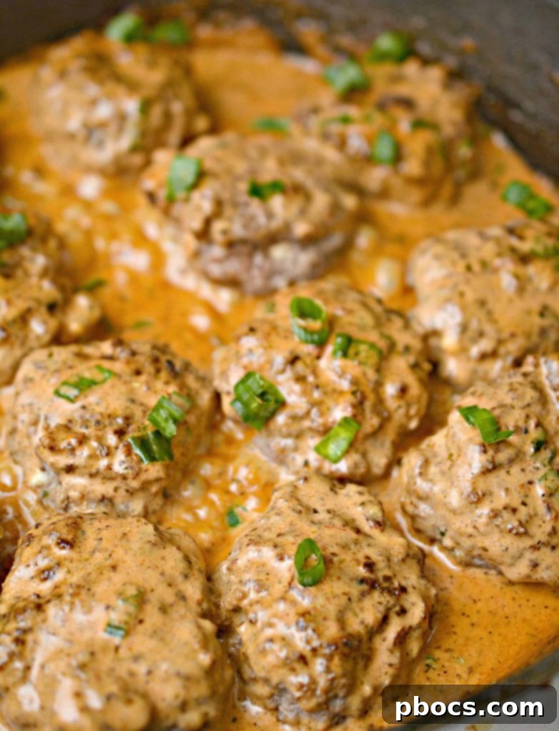 Keto Feta Burgers being tossed and coated in the creamy tomato sauce in a skillet