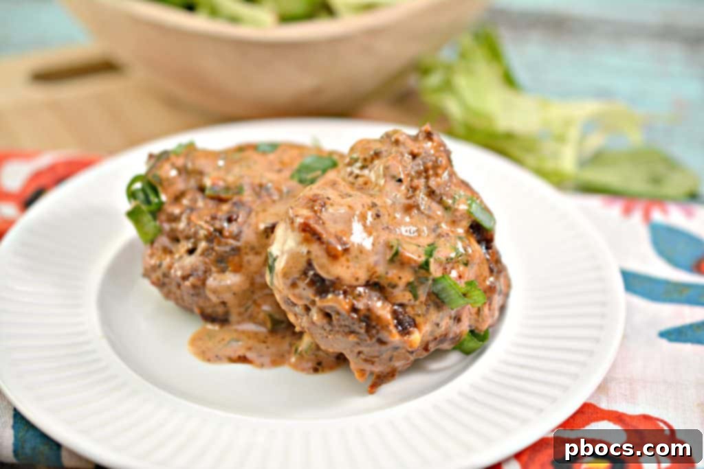 Close-up of a skillet filled with juicy Keto Feta Burgers simmering in tomato cream sauce
