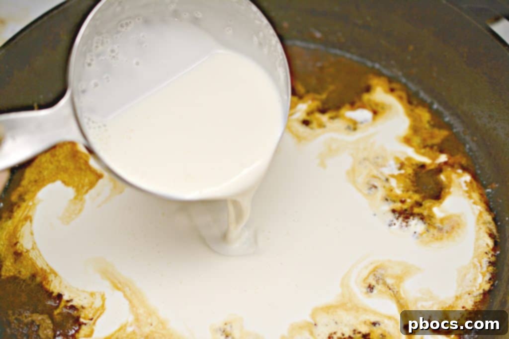 Deglazing a skillet with beef stock after cooking burgers, preparing for sauce