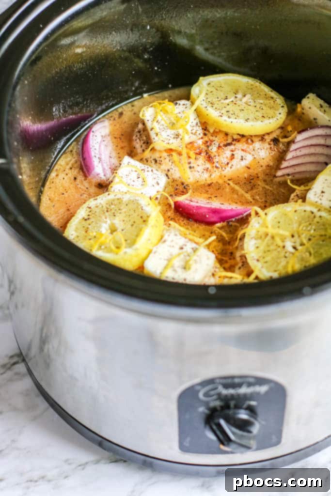 Velvety Lemon Keto Chicken 11 Close-up of chicken, onions, lemon zest, garlic, and butter in the slow cooker
