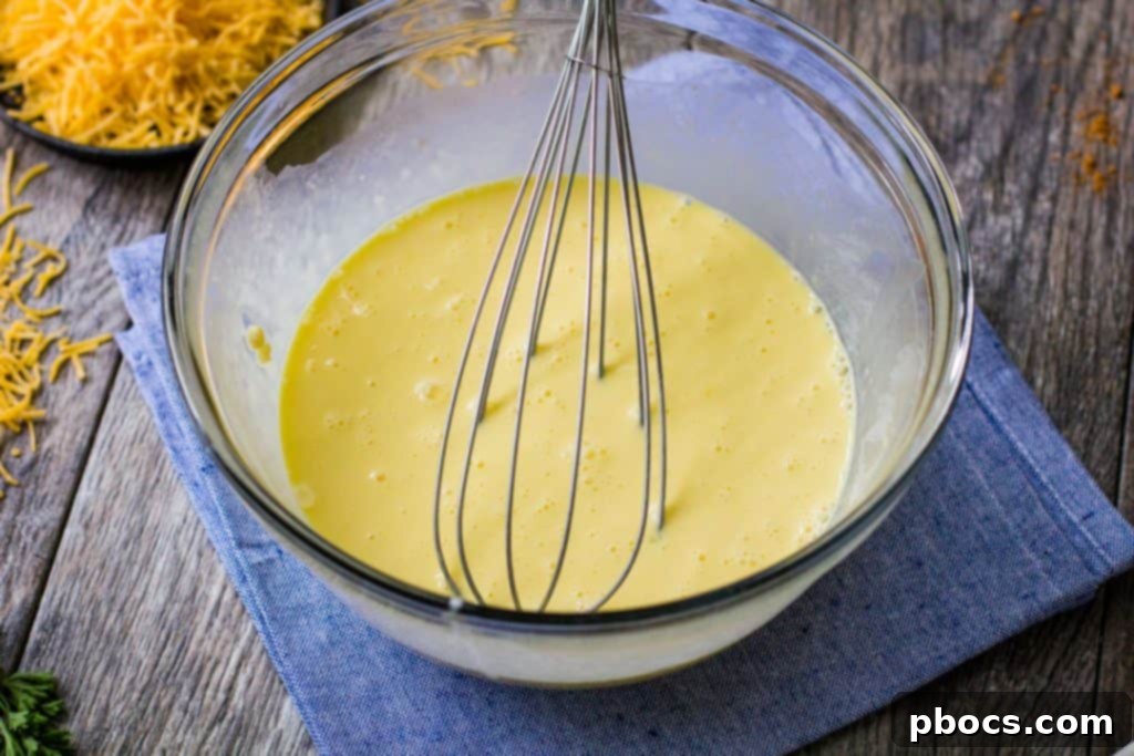Keto Crustless Taco Casserole 10 Egg and cream mixture being poured over ground beef in a skillet