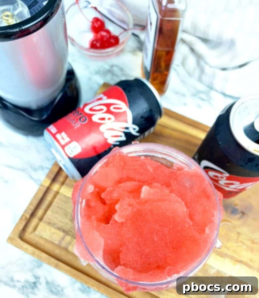 Hand holding a glass of Cherry Frozen Bourbon Slushie garnished with a cherry