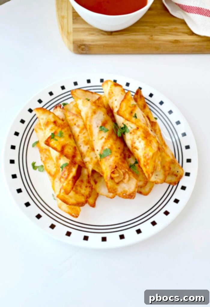 Crispy Keto Buffalo Chicken Taquitos 4 Hand holding a crispy Keto Buffalo Chicken Taquito