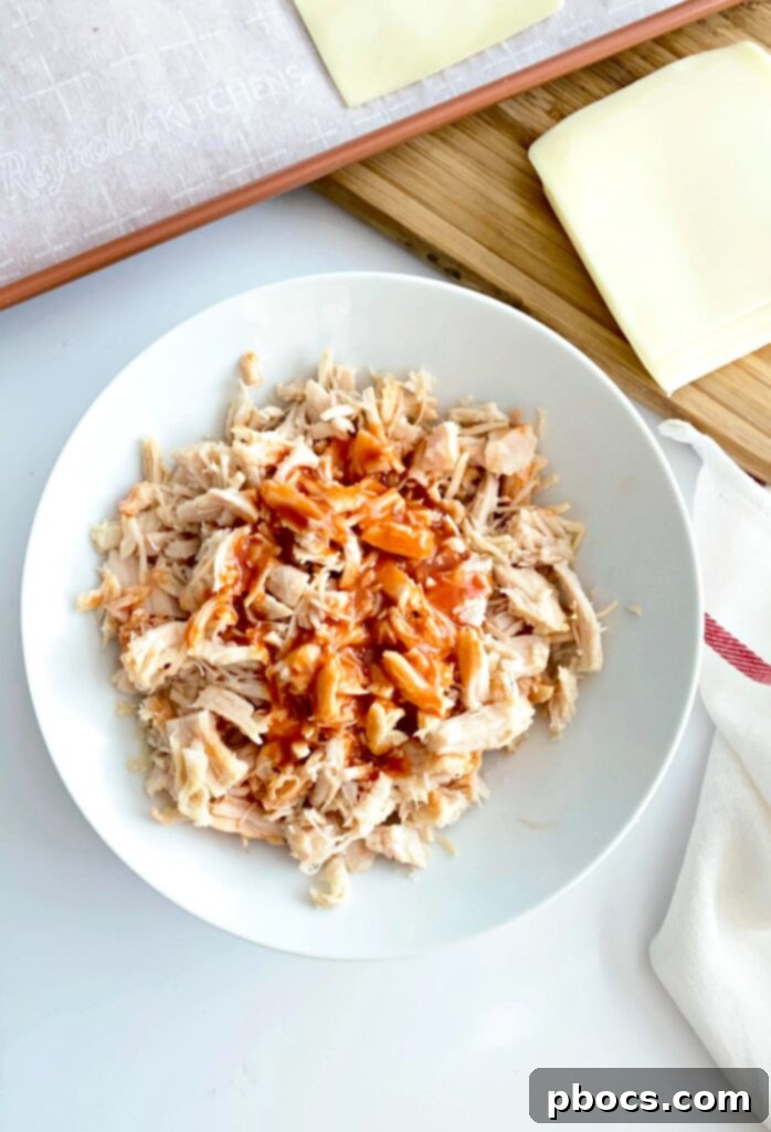 Crispy Keto Buffalo Chicken Taquitos 5 Mixing cooked chicken with Frank's Red Hot Sauce