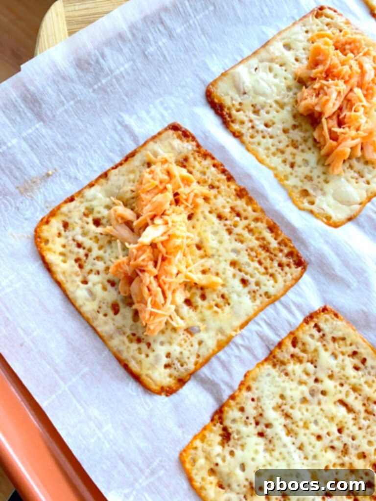 Crispy Keto Buffalo Chicken Taquitos 8 Adding buffalo chicken filling onto baked mozzarella