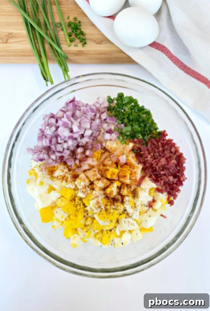 All ingredients for deviled egg salad added to a bowl with chopped eggs.