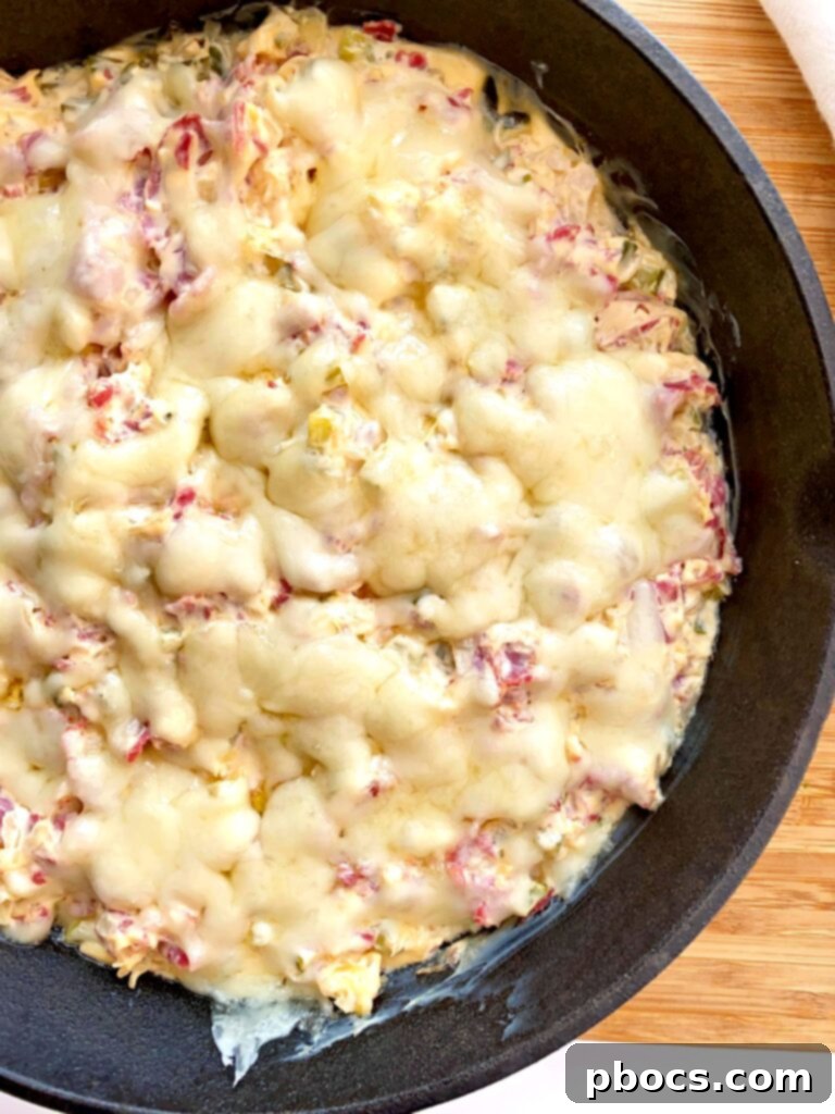 Keto Reuben Dip mixture topped with Swiss cheese in a skillet