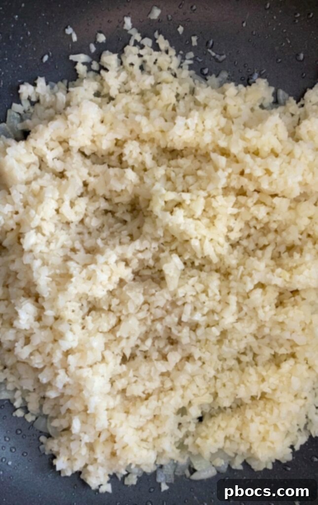 Adding cauliflower rice to the skillet with cooked onions