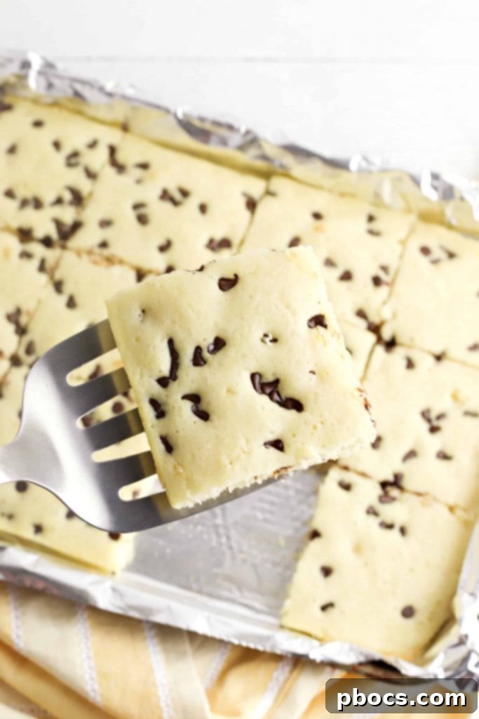A large sheet pan filled with perfectly baked Keto Sheet Pan Pancakes, ready to be cut into individual servings. The golden-brown texture and appealing toppings are visible.