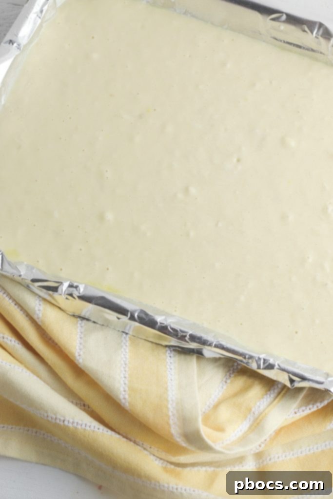Close-up of keto pancake batter being spread evenly onto a parchment-lined baking sheet.