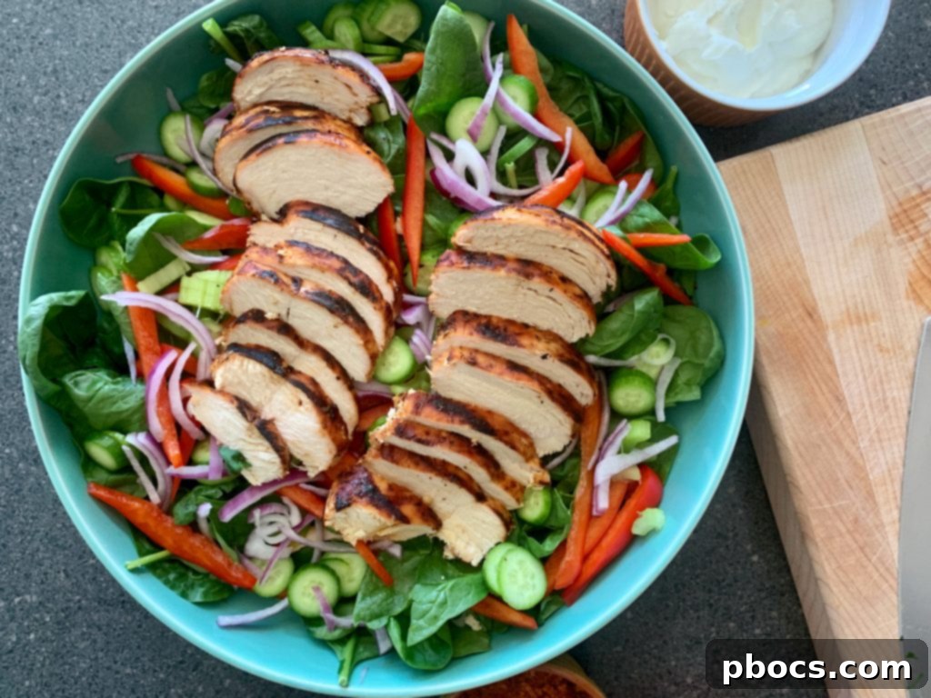 Layering sliced buffalo chicken over a bed of fresh salad greens.
