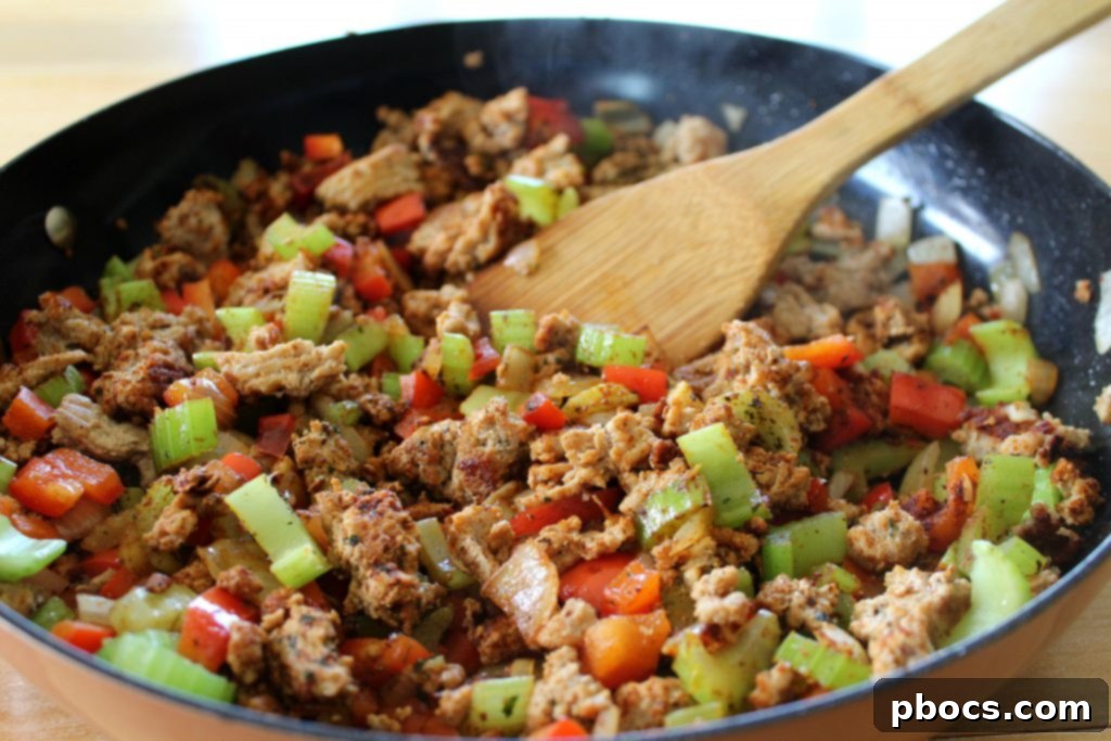 Adding minced garlic and dry spices to the vegetable and meat mixture